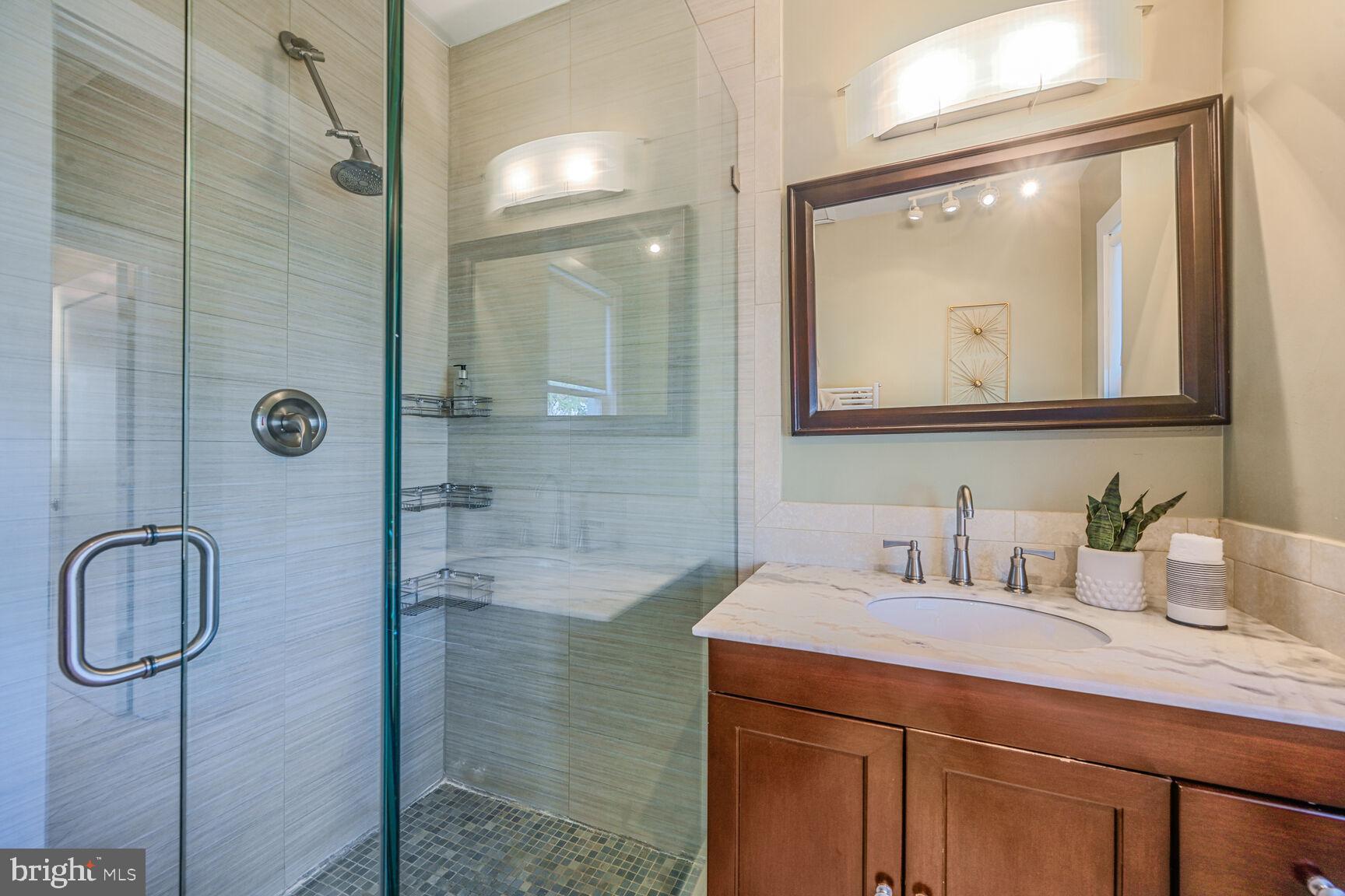 608 Rittenhouse Street Northwest Washington, DC 20011 - Photo 11 of 16 a bathroom with a granite countertop sink a mirror a vanity and shower