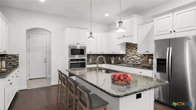 a kitchen with stainless steel appliances granite countertop a sink refrigerator and cabinets