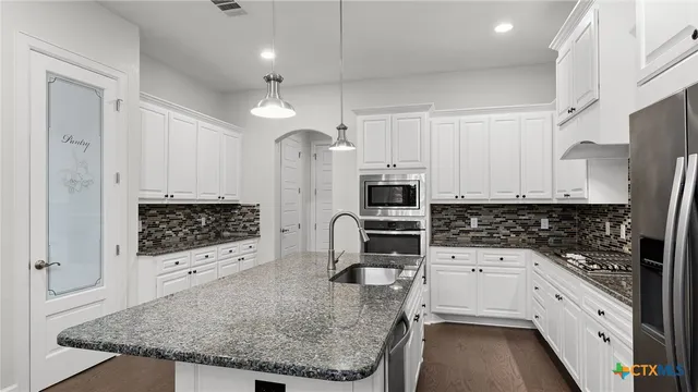 a kitchen with stainless steel appliances a stove a sink a refrigerator and cabinets