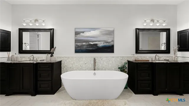 a bathroom with a bathtub and a double vanity sink