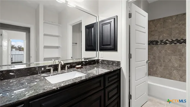 a bathroom with a granite countertop sink a mirror a bathtub and shower