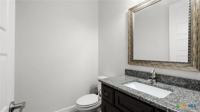 a bathroom with a granite countertop toilet sink and mirror