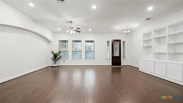 a view of an empty room with a window and wooden floor