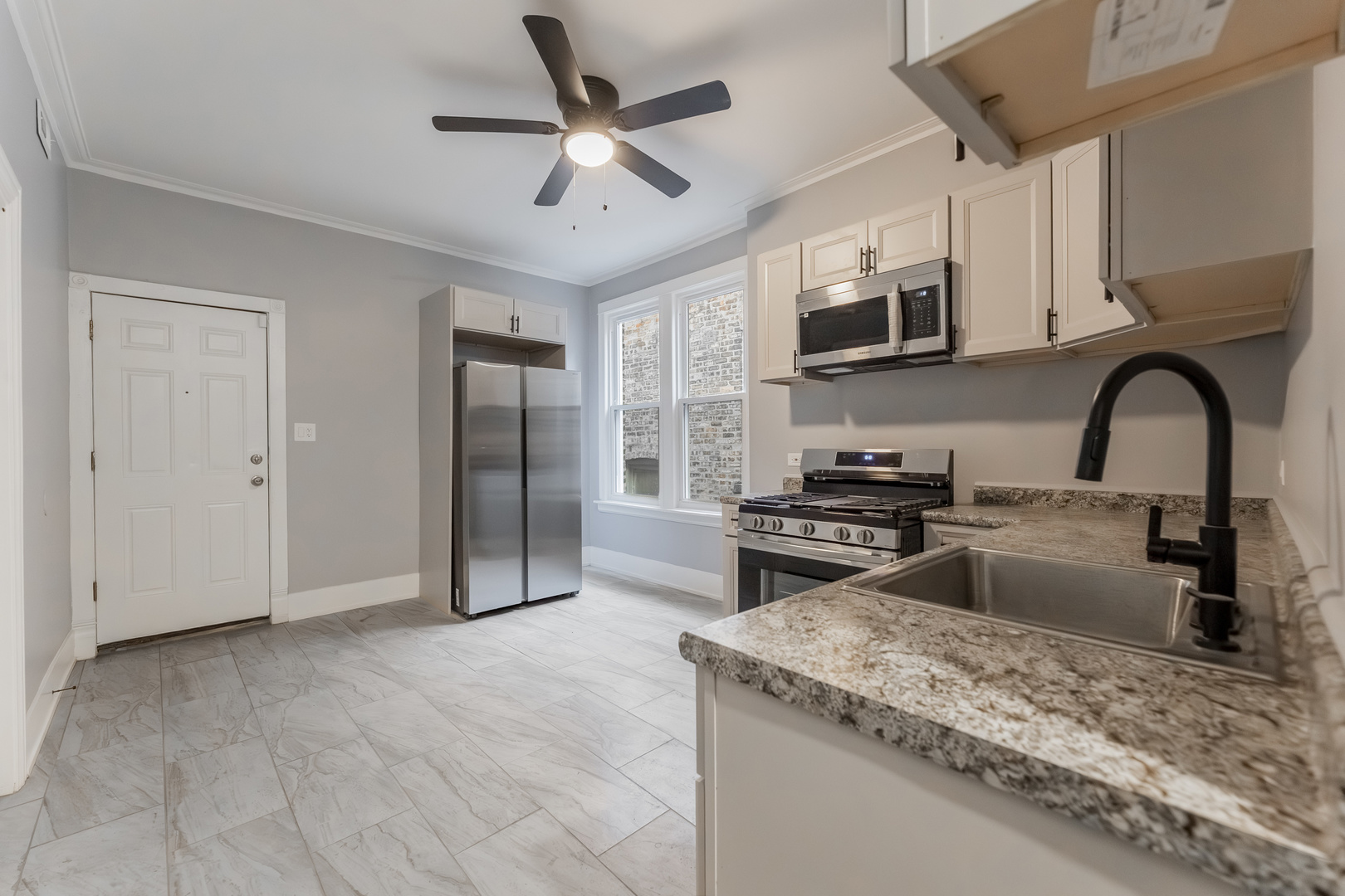 3821 West Fillmore Street, Unit 2B Chicago, IL 60624 - Photo 3 of 11 a kitchen with stainless steel appliances granite countertop a stove top oven a sink a refrigerator with a dining table and chairs