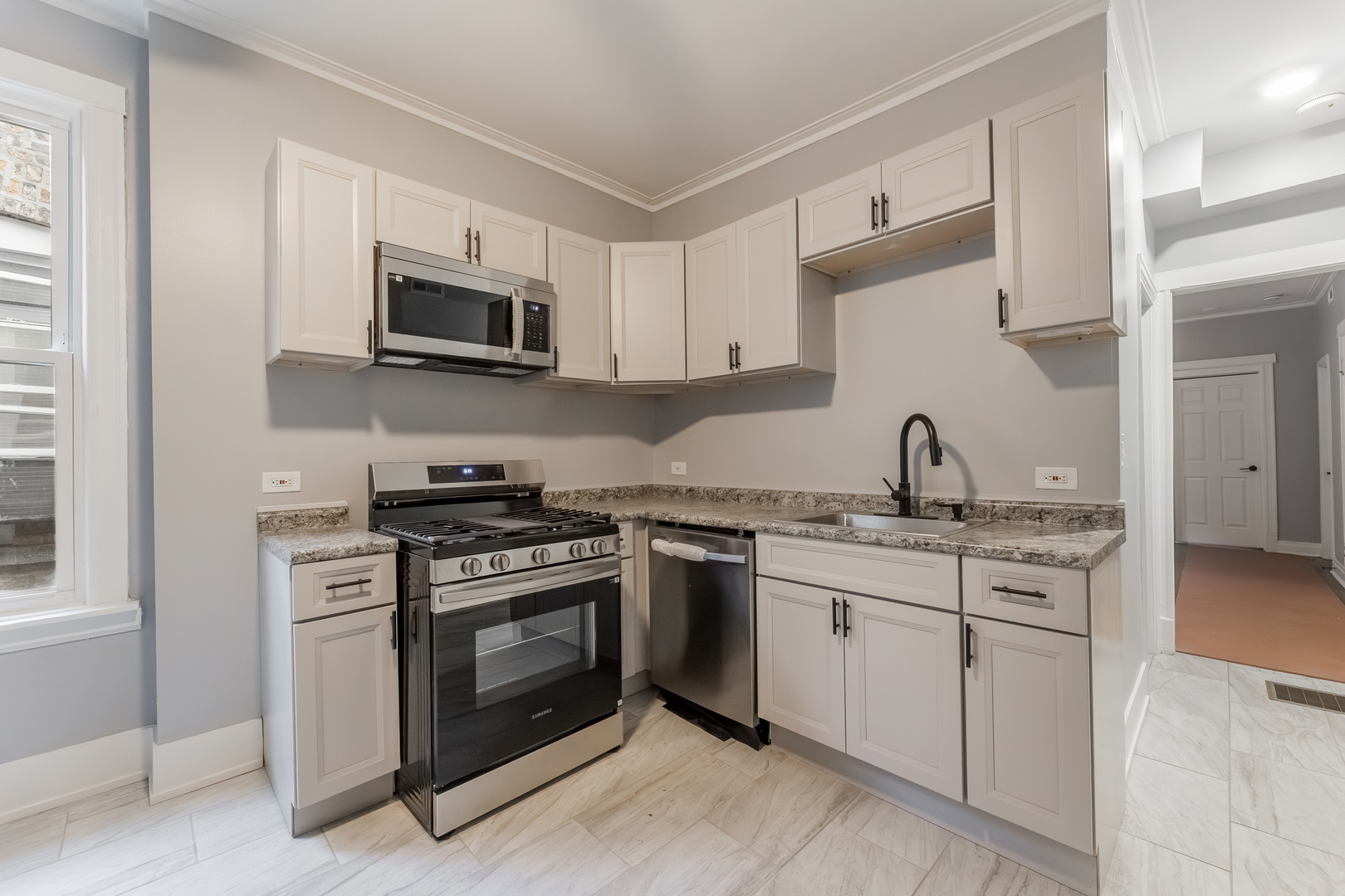 3821 West Fillmore Street, Unit 2B Chicago, IL 60624 - Photo 5 of 11 a kitchen with stainless steel appliances granite countertop white cabinets a sink a stove and a microwave