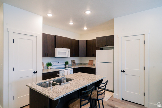 220 Spring Creek Parkway Providence, UT 84332 - Photo 5 of 17 Kitchen featuring a dual-basin island sink, white appliances, dark wood-finish cabinetry, light-toned countertops, and recessed lighting