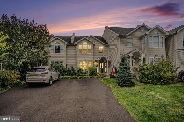 a view of a grey house with a small yard and large trees