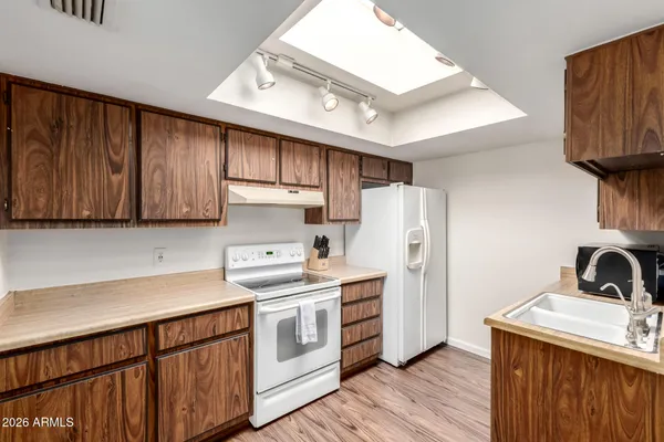 a kitchen with stainless steel appliances a sink a stove a refrigerator cabinets and wooden floor