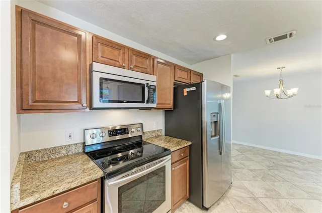 a kitchen with stainless steel appliances granite countertop a stove a microwave and a refrigerator