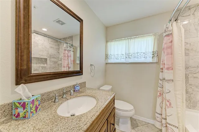 a bathroom with a granite countertop sink mirror vanity and toilet