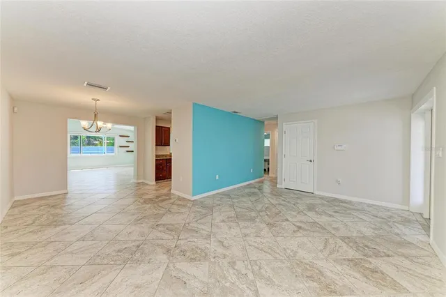 a view of an empty room with kitchen and a window