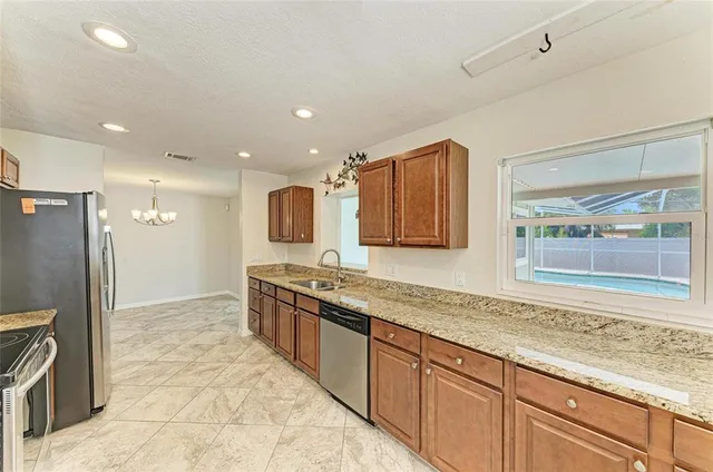 a large kitchen with stainless steel appliances granite countertop a refrigerator and a sink