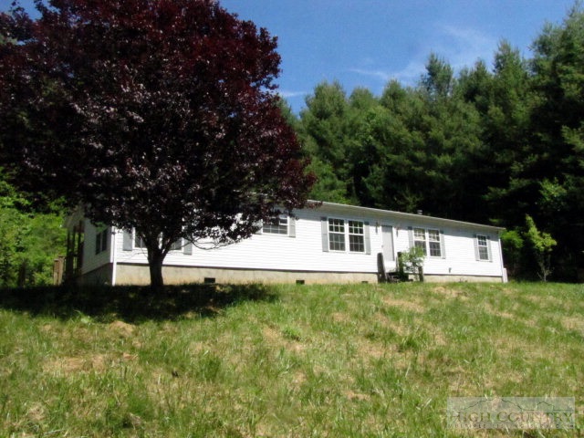 3970 Silas Creek Road Lansing, NC 28643 - Photo 1 of 16 a white house that has a big yard with large trees