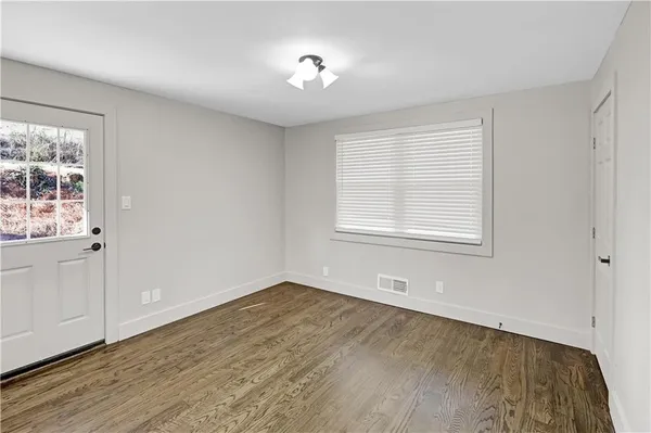 a view of an empty room with wooden floor and a window