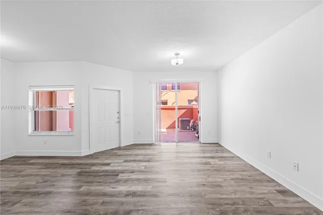 an empty room with wooden floor and fan