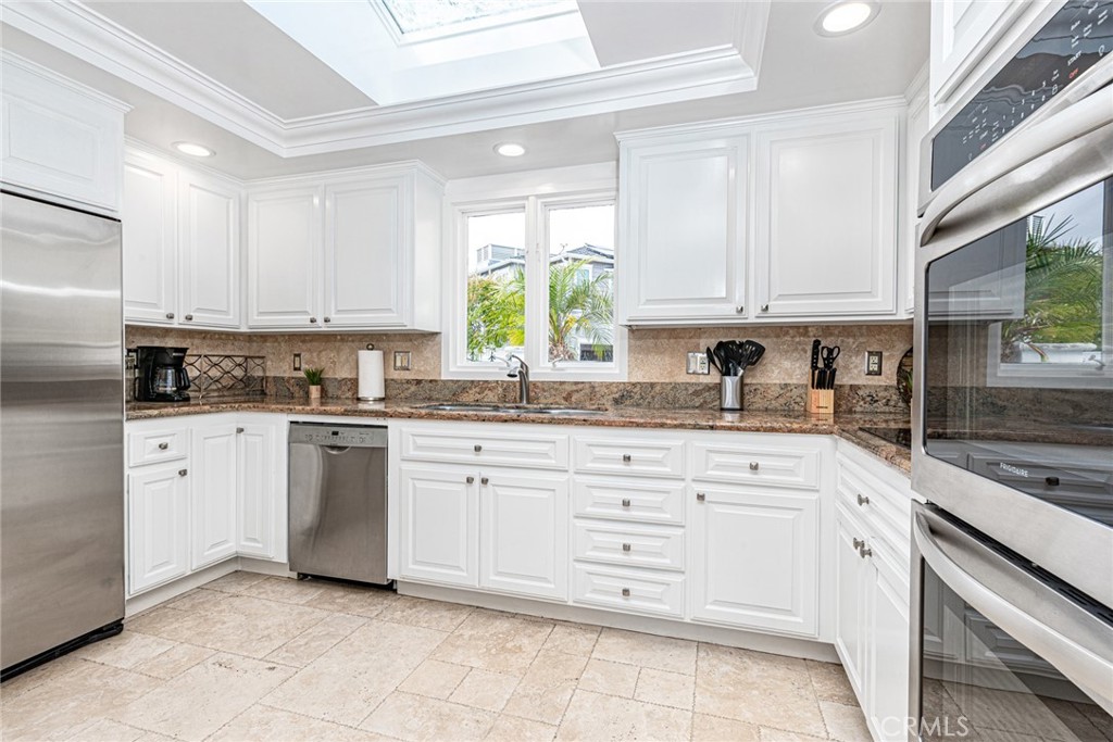 3717 Channel Place Newport Beach, CA 92663 - Photo 19 of 41 a kitchen with granite countertop white cabinets white appliances with a sink and dishwasher