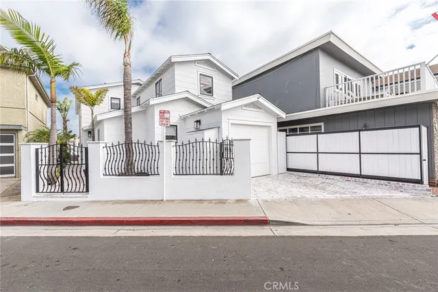a view of a white house with large windows and palm trees