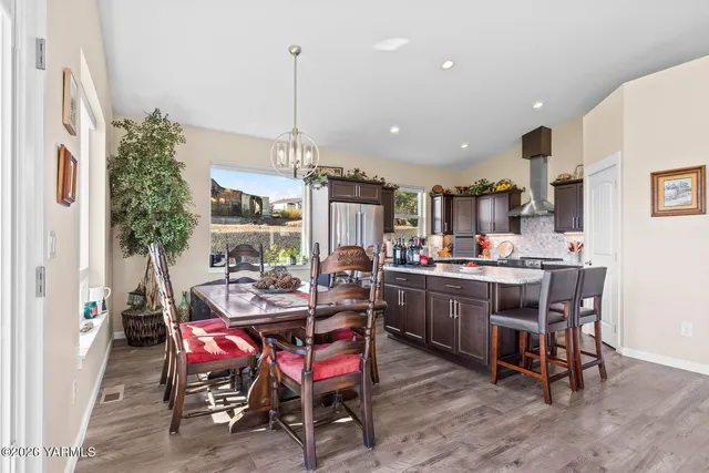 a view of a dining room and livingroom with furniture wooden floor a rug a painting and a chandelier