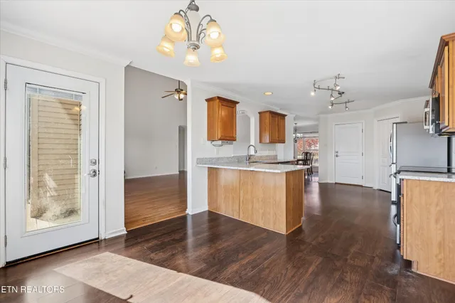 a kitchen with stainless steel appliances granite countertop a sink dishwasher a stove and a refrigerator with wooden floor