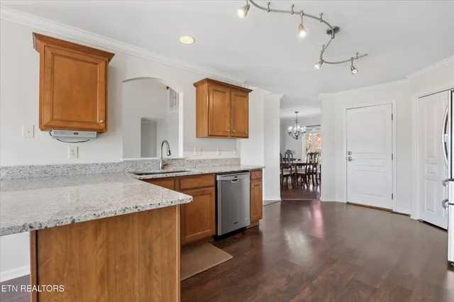 a kitchen with stainless steel appliances granite countertop a refrigerator a stove top oven a sink dishwasher and white cabinets with wooden floor