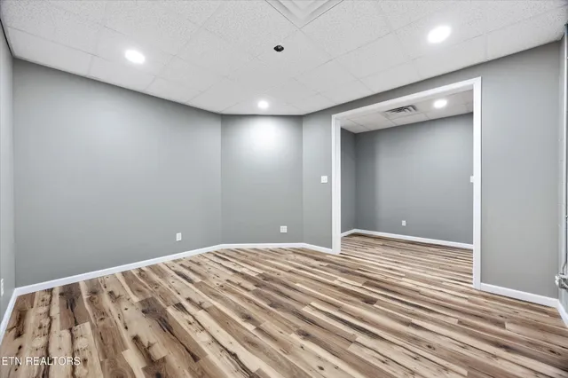a room with wooden floor pool table and windows