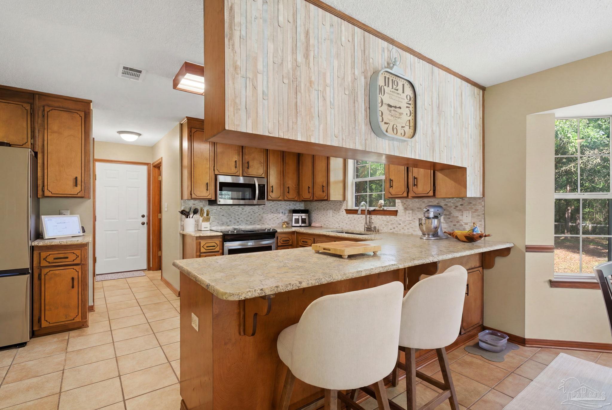 6870 Martin Road Milton, FL 32570 - Photo 10 of 48 a kitchen with stainless steel appliances granite countertop a sink a stove a refrigerator cabinets and chairs