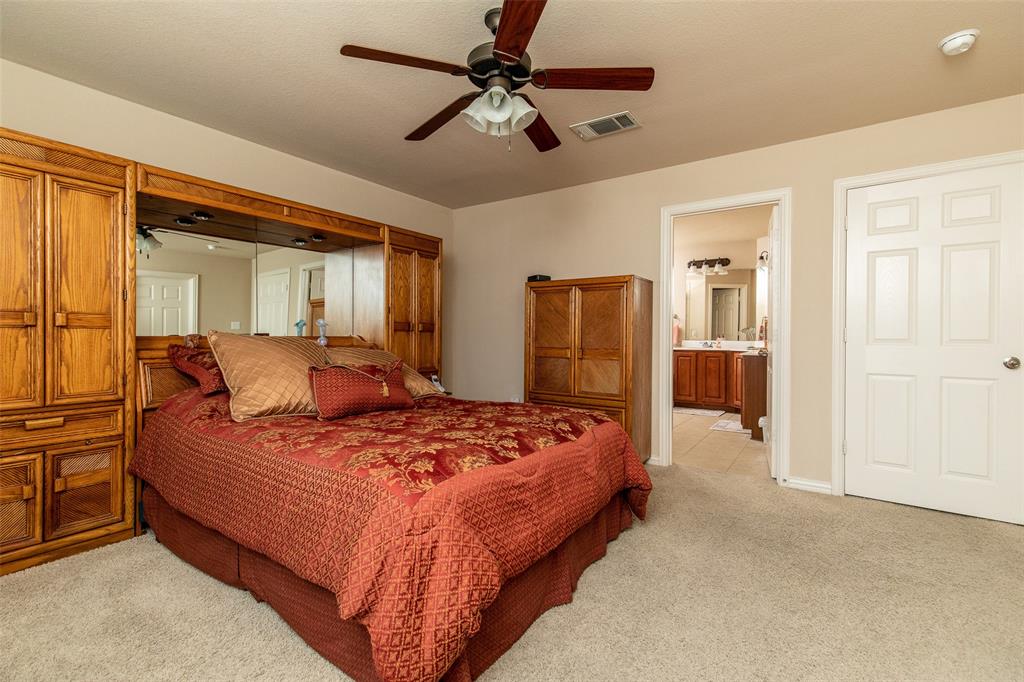 3118 Bedford Road Bedford, TX 76021 - Photo 19 of 29 Carpeted bedroom featuring a ceiling fan with integrated lighting, a white paneled door, and a doorway to a bathroom with dual vanities