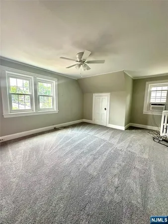 an empty room with windows and chandelier fan