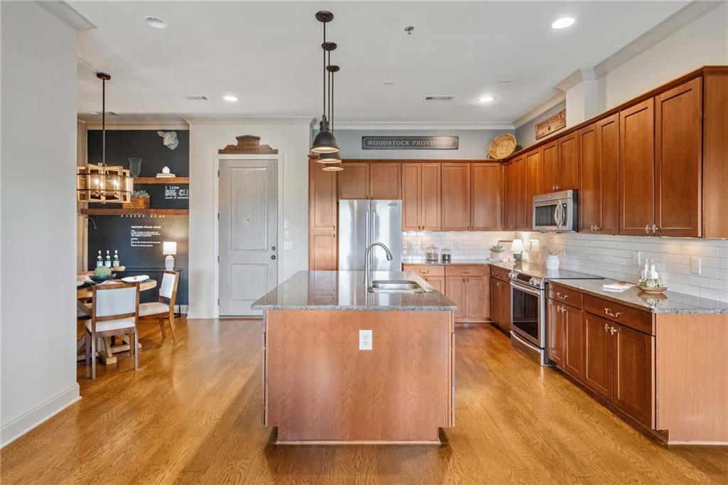 360 Chambers Street, Unit 210 Woodstock, GA 30188 - Photo 8 of 36 a large kitchen with stainless steel appliances kitchen island granite countertop a refrigerator a stove top oven a sink and island with wooden floor