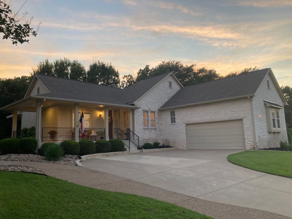 144 Cattle Trail Way Georgetown, TX 78633 - Photo 35 of 37 An inviting front porch welcomes you to this home with a stone and stucco exterior, set against a vibrant sunset.