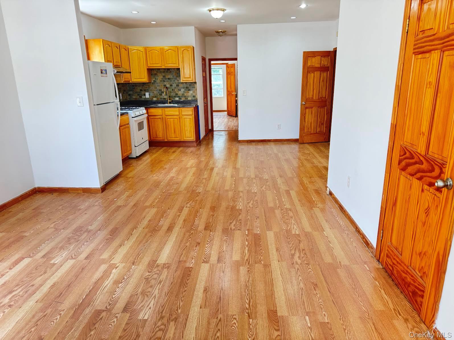 a large kitchen with a sink and wooden floor