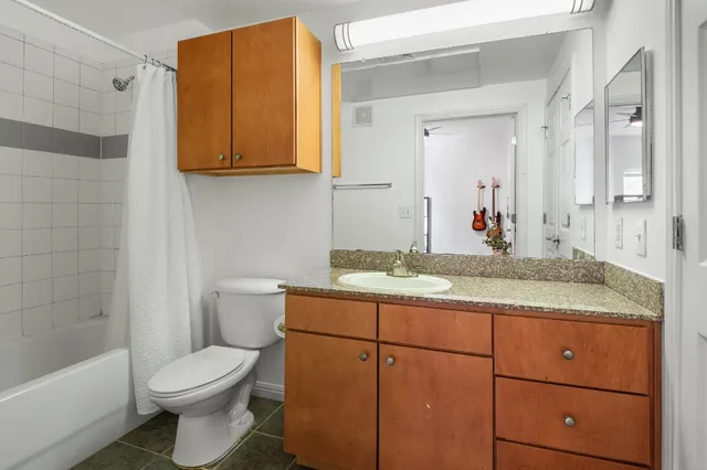 a bathroom with a granite countertop toilet sink and mirror