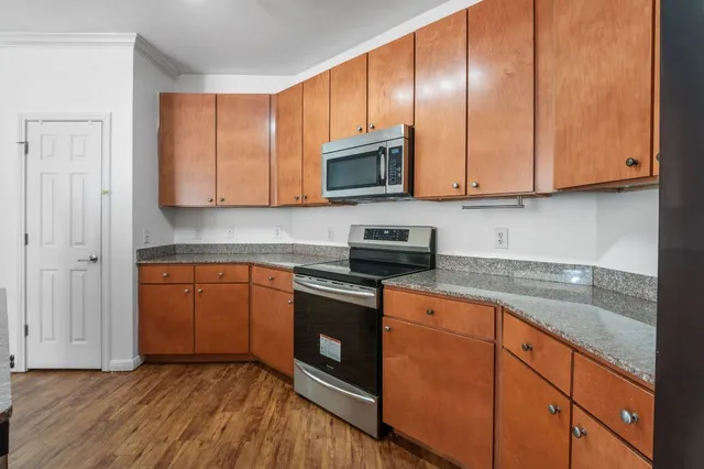 a kitchen with granite countertop wooden cabinets stainless steel appliances and a sink