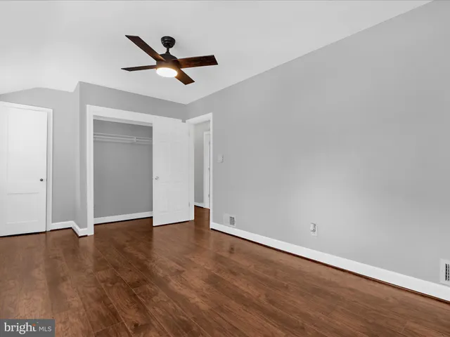 an empty room with wooden floor ceiling fan and window