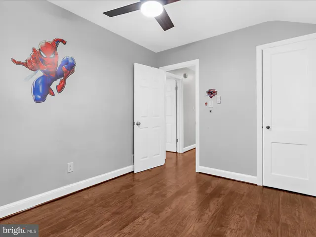 an empty room with wooden floor and ceiling fan