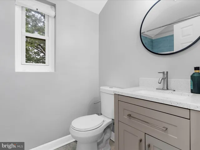 a bathroom with a granite countertop toilet sink and mirror