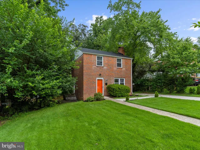 a view of a house with a yard and a large tree