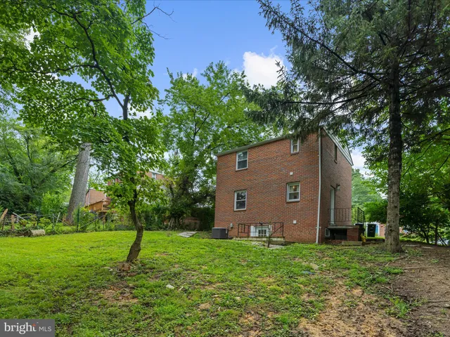 a backyard of a house with plants and large tree