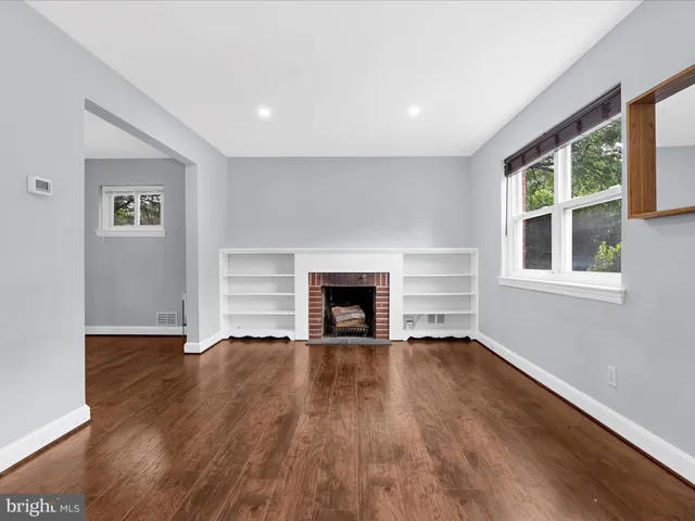 a view of an empty room with window and wooden floor
