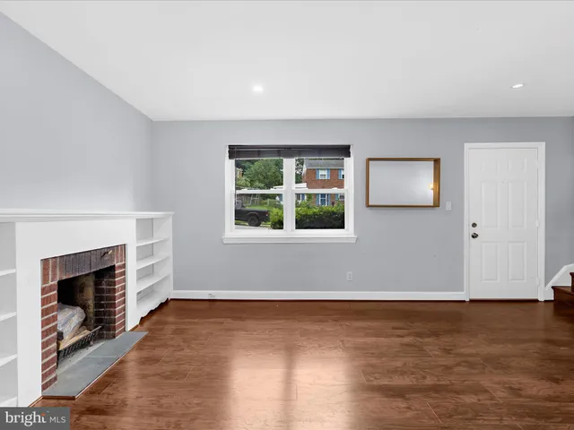 an empty room with windows fireplace and wooden floor