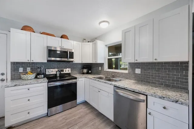 a kitchen with granite countertop white cabinets sink and stainless steel appliances