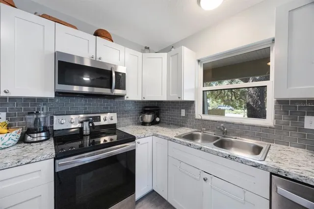 a kitchen with stainless steel appliances granite countertop a sink a stove a microwave and wooden cabinets