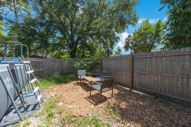 a view of backyard with wooden fence and a large tree