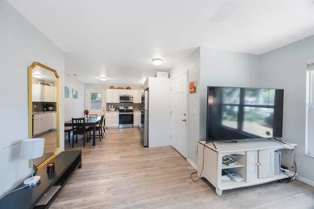 a living room with stainless steel appliances furniture and a flat screen tv