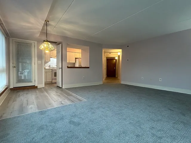 an empty room with chandelier fan and windows