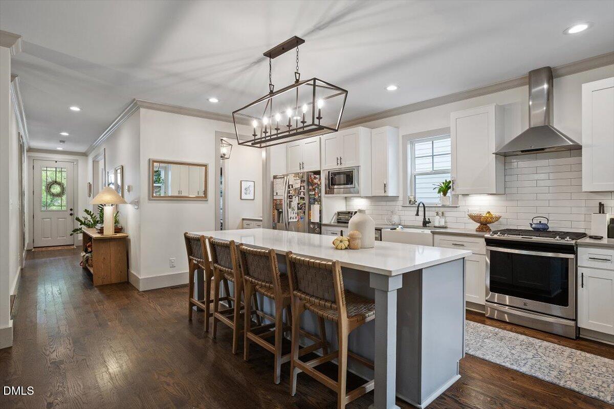 1303 Nottingham Road Raleigh, NC 27607 - Photo 8 of 33 a kitchen with stainless steel appliances a kitchen island hardwood floor sink stove dining table and chairs