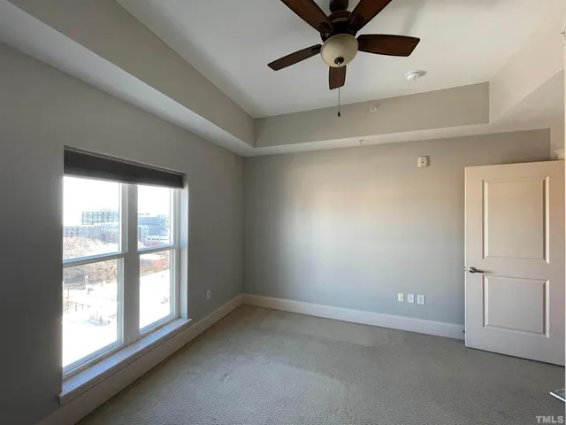 an empty room with windows and fan