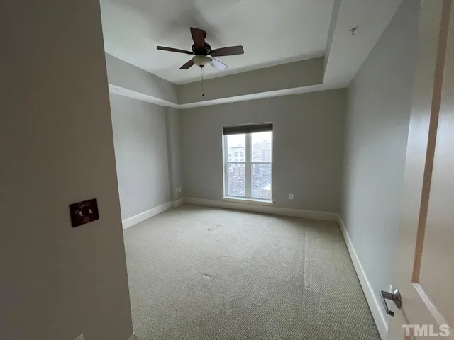 an empty room with ceiling fan and window