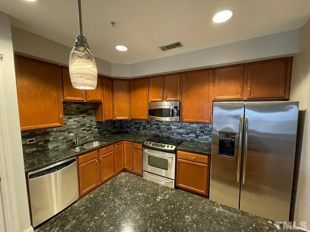 a open kitchen with stainless steel appliances granite countertop a refrigerator a sink dishwasher a stove and white countertops with wooden floor