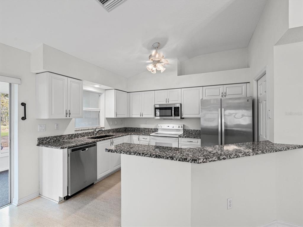 11621 Holly Ann Drive New Port Richey, FL 34654 - Photo 13 of 59 a kitchen with stainless steel appliances granite countertop a sink stove and refrigerator